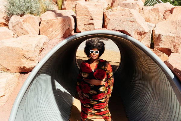 Kam Franklin stands inside a giant tube in front of some rocks.
